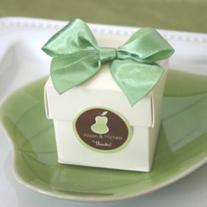 a small white box with a green bow and label on a plate