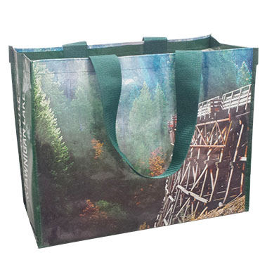 a green laminated woven bag with a picture of forest and a bridge
